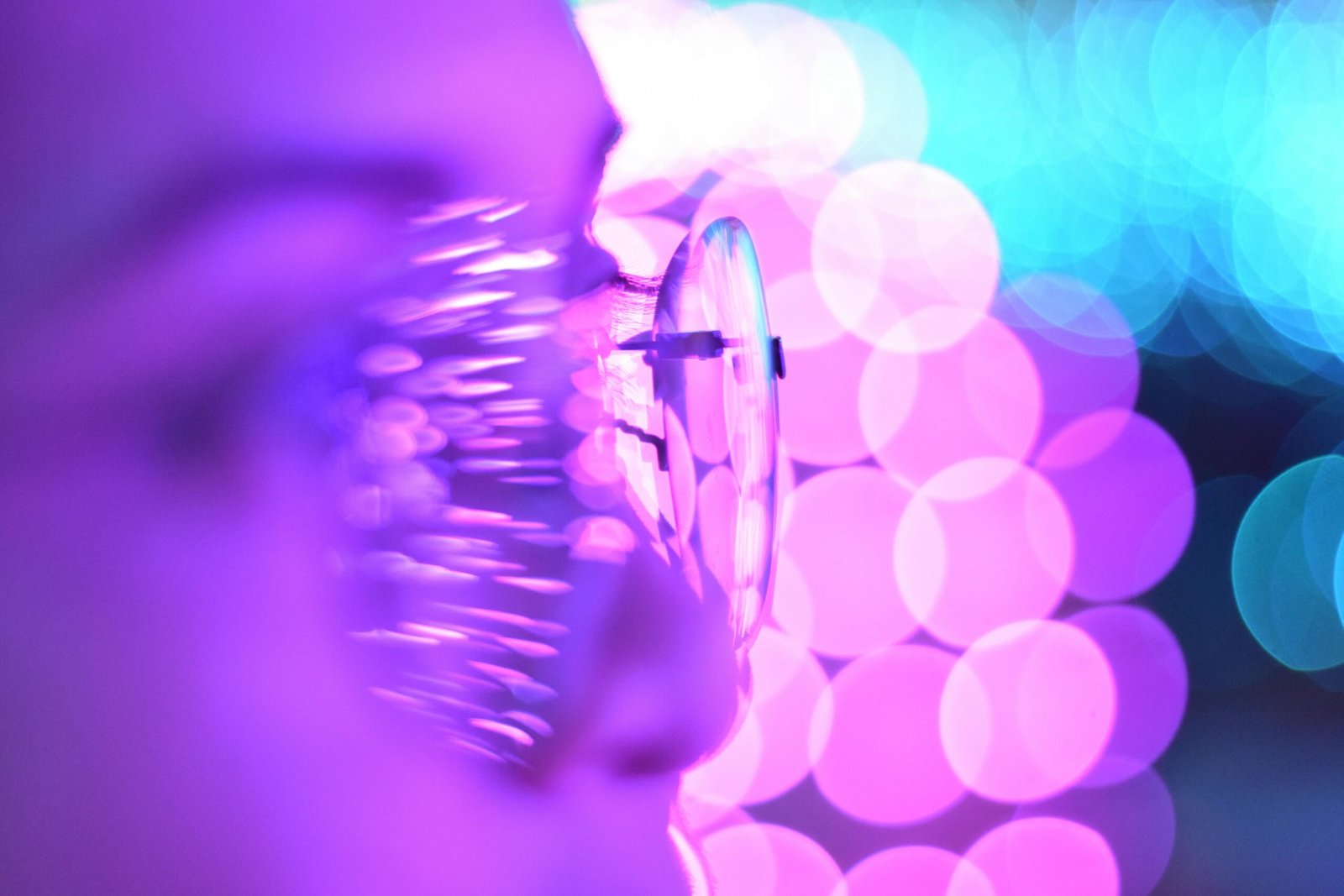 Close-up photo of eyeglasses with bright purple and blue bokeh lights creating an abstract aesthetic.